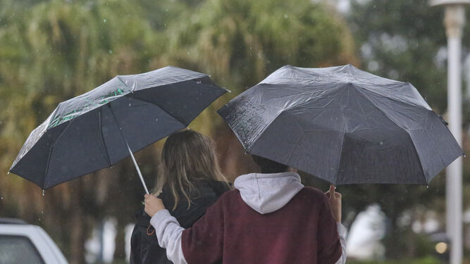 Dos jóvenes se protegen de la lluvia.